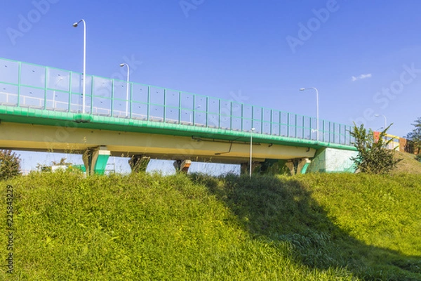 Fototapeta Sound absorbing screens on the highway and overpass and green grass on the slope.Metal frames filled with glass. Modern technology in Warsaw,Poland.