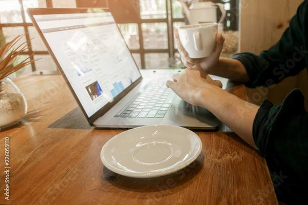 Fototapeta Close up young man working with his computer in coffee shop