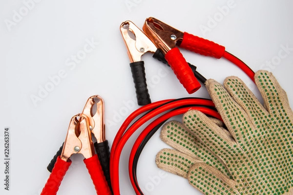 Fototapeta Jump start with crocodile clip or wire red and black clamps for recharge the battery car and protective gloves on a white background. Top view