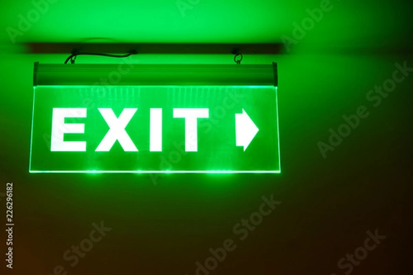 Obraz Front face raised view of green emergency fire exit sign hanging on the ceiling