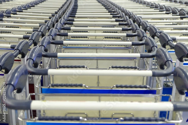 Fototapeta Handles of empty carts in straight rows