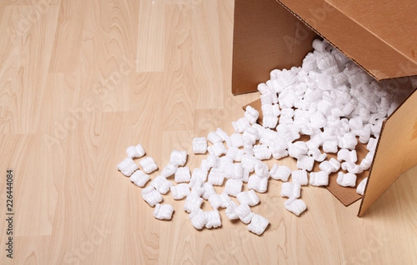 Fototapeta Open cardboard box with packing peanuts in the box and on the floor