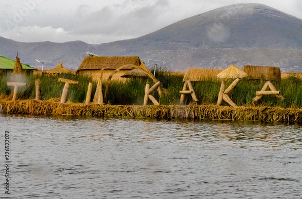 Fototapeta Titikaka sign made of totora by the Uros in a floating Island with a mountain on the back