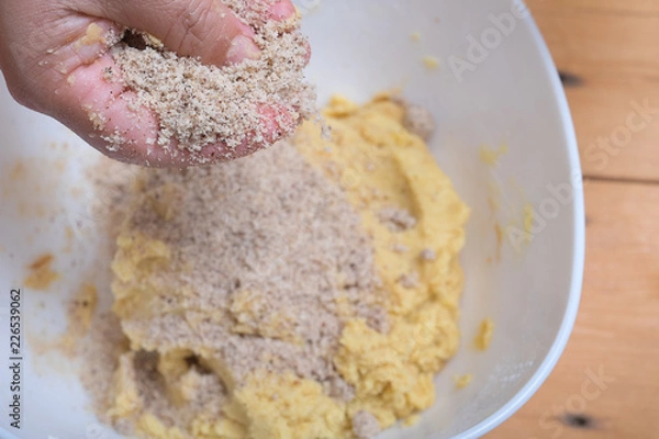 Fototapeta Close up of female hands making hazelnut cookies from sliced almonds and flour with coffee powder .