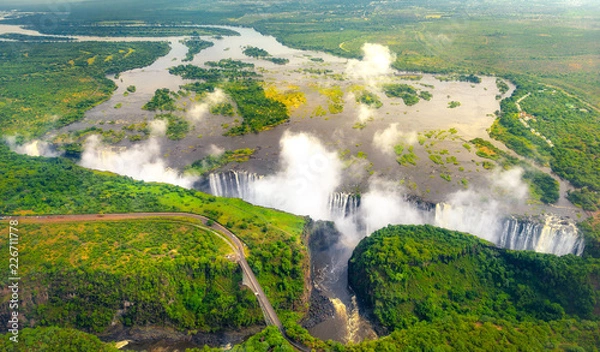 Obraz Wodospady Wiktorii w Zimbabwe i Zambii, zdjęcie z helikoptera z lotu ptaka, zielony las wokół niesamowitych majestatycznych wodospadów Afryki. Livingston Bridge nad rzeką