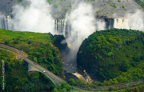 Obraz Victoria Falls in Zimbabwe and Zambia, Aerial helicopter photo, green forest around amazing majestic waterfalls of Africa. Livingston Bridge above the river