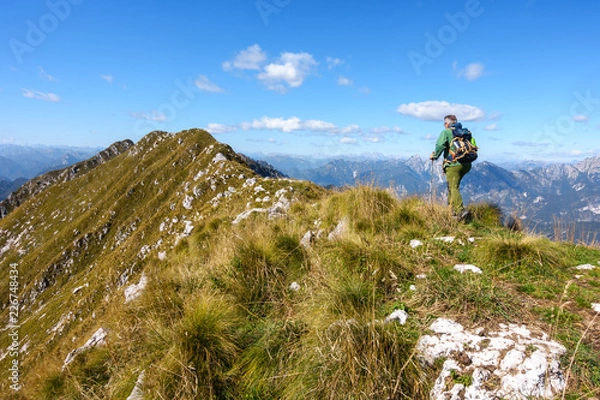 Obraz Man hiker walking on top of mountain against blue sky.