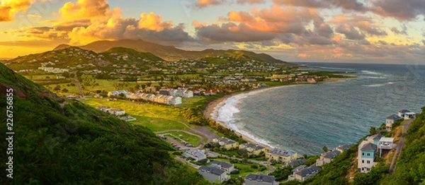 Obraz Panorama Saint Kitts i jego stolicy Basseterre podczas zachodu słońca, piękne zielone góry i plaża na rajskiej karaibskiej wyspie w niesamowitych zielono-pomarańczowych kolorach. Saint kitts i nevis