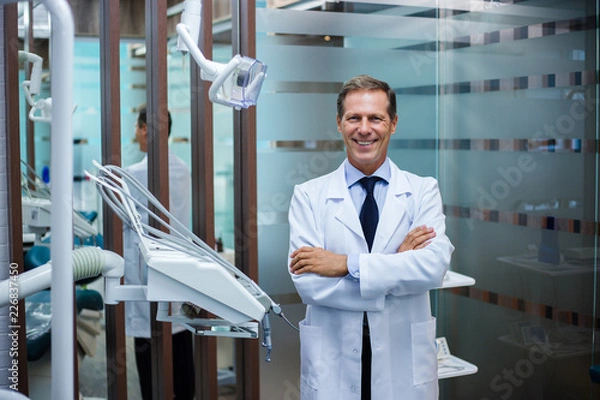 Fototapeta  Mr. Doctor. Cheerful dentist looking at camera with smile while standing in dentist’s office