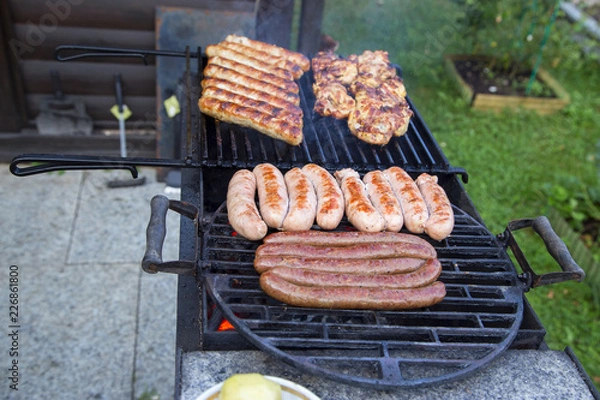 Obraz Приготовление вкусных колбасок и мяса на гиле.Горизонтально.