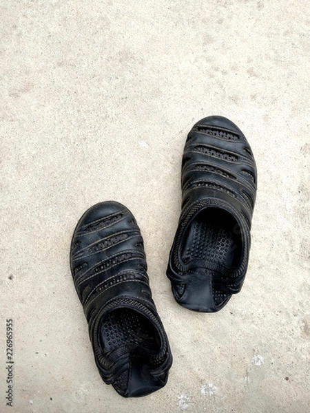 Obraz  Black rubber sandals isolated on the white concrete background with shadow.Black rubber sandals isolated on the white concrete background with shadow.