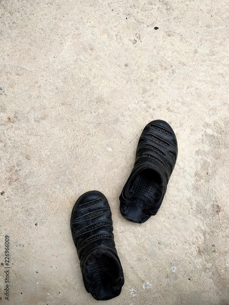 Obraz  Black rubber sandals isolated on the white concrete background with shadow.Black rubber sandals isolated on the white concrete background with shadow.