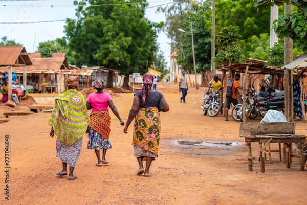Obraz Wioska Togoville w Togo. Kobiety chodzące w afrykańskich strojach po wiosce. Religia Voodoo w Togo w Afryce Zachodniej. Targowiska voodoo w Togoville i Lomé.