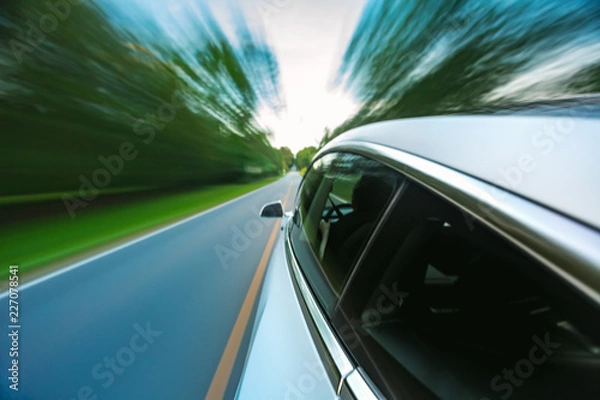 Fototapeta Luxury vehicle driving down the road with motion blur