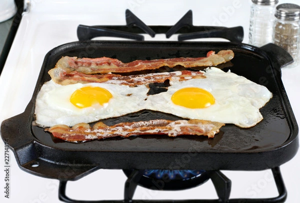 Obraz Eggs and Bacon Frying on Cast Iron Pan
