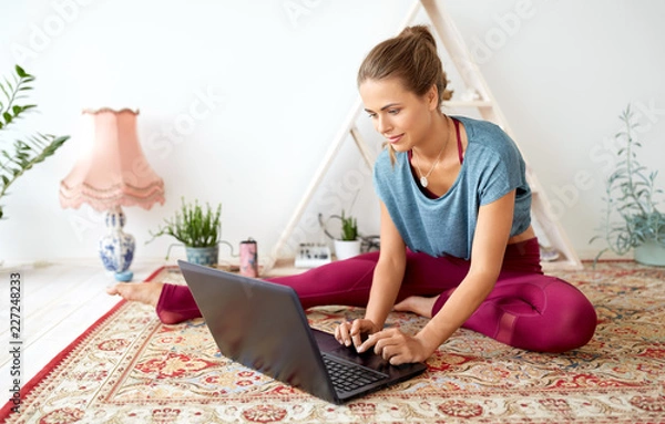 Fototapeta fitness, technology and healthy lifestyle concept - woman with laptop computer at yoga studio