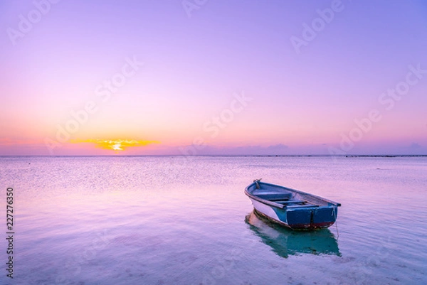 Obraz Mauritius Boat in the sea with pink and purple colors during Sunset in beautiful Mauritius paradise landscape. Mauritius nature view of colorful sky and light of sun. Reflection on the sea near beach