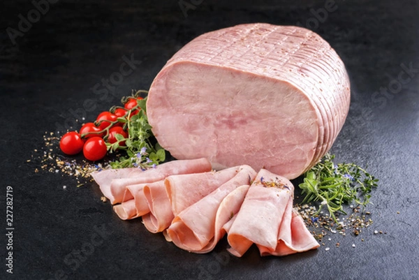 Obraz Tradycyjna niemiecka szynka gotowana w plasterkach i rozcięta jako zbliżenie na czarnej tablicy