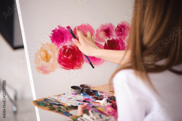 Obraz Сute girl artist paints on canvas painting on the easel. Model in the studio