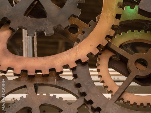 Fototapeta Low angle view to part of cogwheels. Vintage iron machine part in store. Abstract background of old industrial.