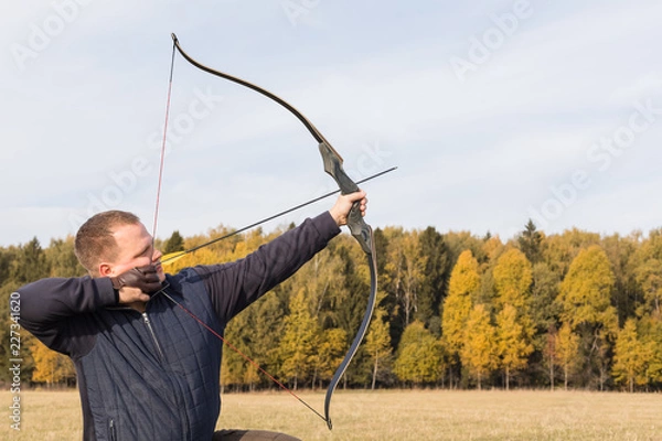 Fototapeta Athlete aiming at a target and shoots an arrow. Archery