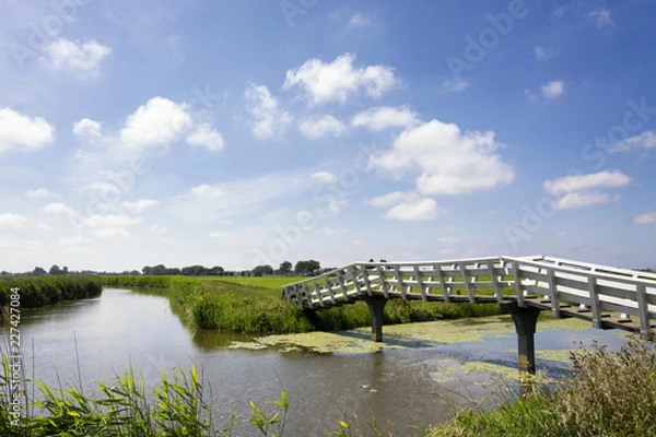 Obraz Typical Dutch landscape with green meadows, grass, bridge, water, blue sky and clouds