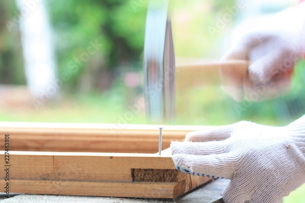Obraz Carpenter hammer nail into a wooden frame