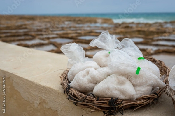Obraz Salinas. Salt Pans or salters at the background with salt bags ready for sale in a basket or bowl outdoor. Hand harvest salt in Gozo Island Marsalforn. space for text.