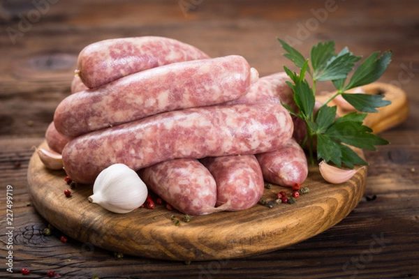 Fototapeta Raw sausages on the wooden board