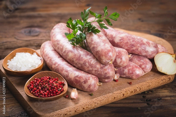 Obraz Surowe kiełbasy na drewnianej desce