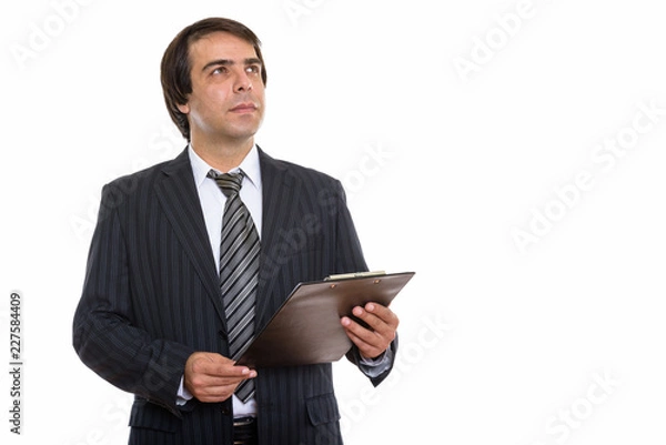 Fototapeta Studio shot of young Persian businessman holding clipboard while