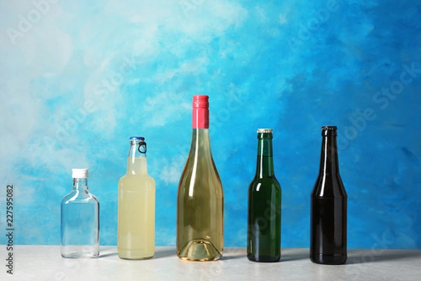 Fototapeta Bottles with different alcoholic drinks on table against color background