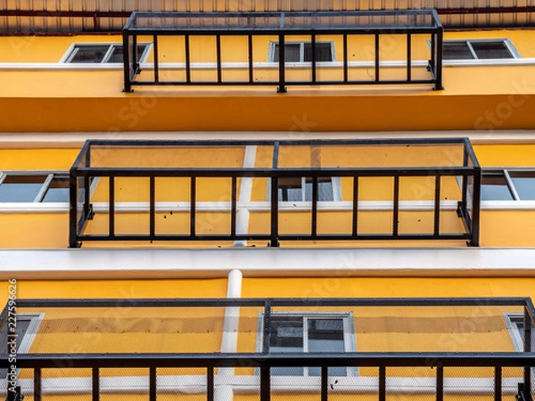 Fototapeta Illuminated image of building with low angle view, exterior design by make iron grate outside building. Level of building with look up view in sunny day. Fire exit design by iron grate outside windows