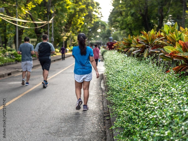 Fototapeta Selective focused on foreground at pathway with emotion blurred background. Rear view of people who are walking and running in public park. Low selection view of the way forward.