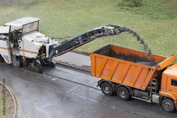 Obraz Road milling machine removes old asphalt and loads milled asphalt into the dump truck. Road repair process. High angle view