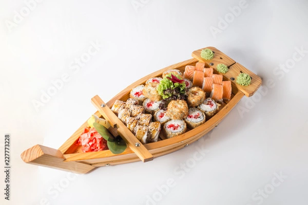 Fototapeta Wooden boat with lots of sushi with ginger and wasabi