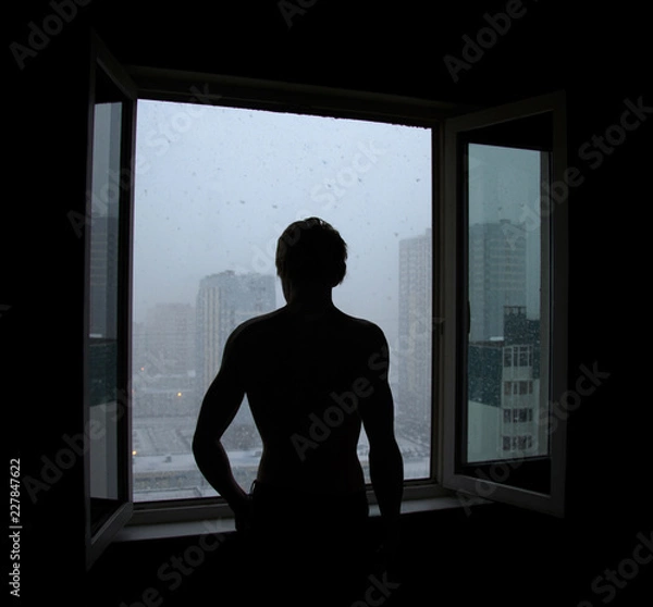Fototapeta dark silhouette of a man near the window followed by snow