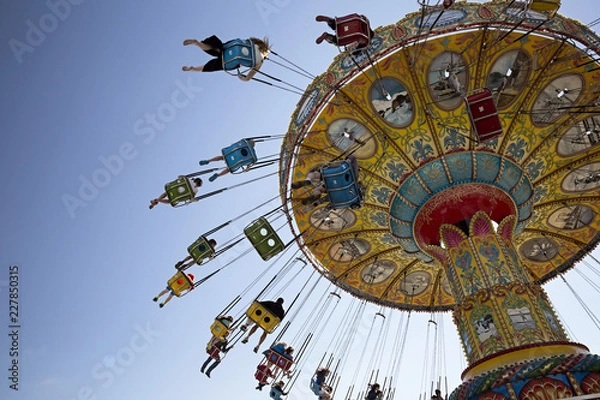 Obraz Families having fun riding a carousel swing high above the crowds
