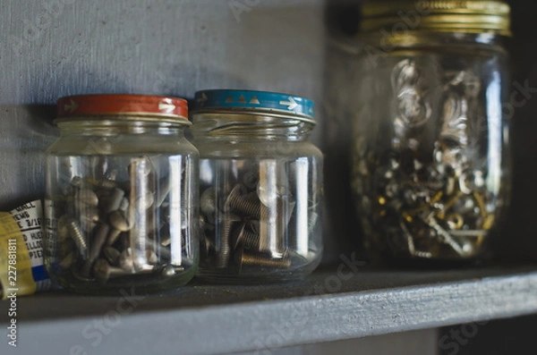Obraz A wooden shelf in the shop with the jars full of screws. 