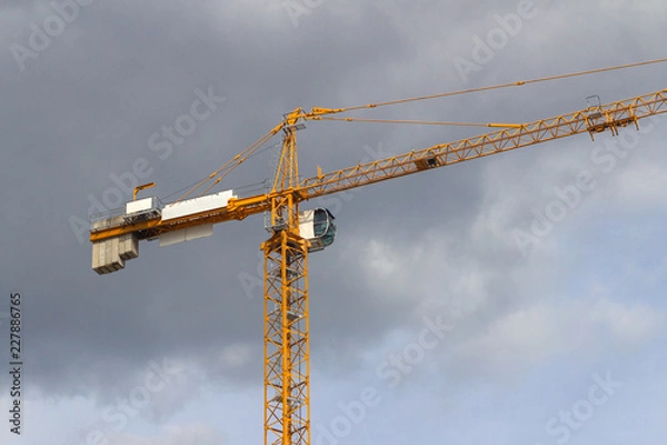 Fototapeta Yellow tower crane on the background of rain clouds
