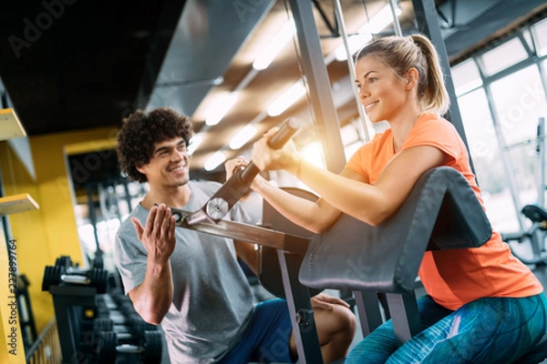 Fototapeta Young beautiful woman doing exercises with personal trainer
