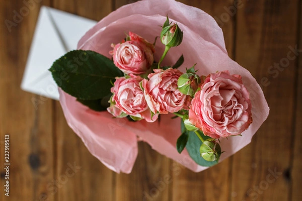 Fototapeta a bouquet of roses in a vase with envelope on wooden background