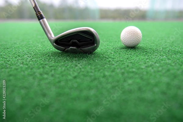 Obraz Golf club and ball on a synthetic grass mat at a practice range.