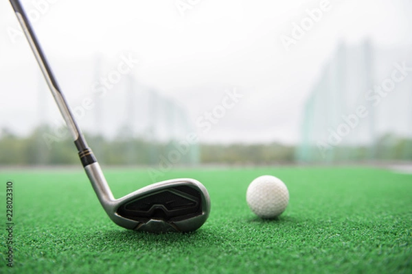 Obraz Golf club and ball on a synthetic grass mat at a practice range.