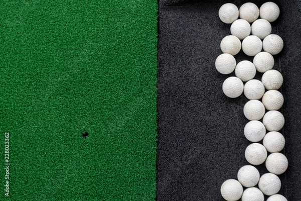Obraz Golf balls on a synthetic grass mat at a practice range.