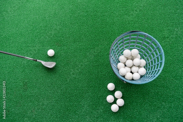 Obraz Golf club and balls on a synthetic grass mat at a practice range.