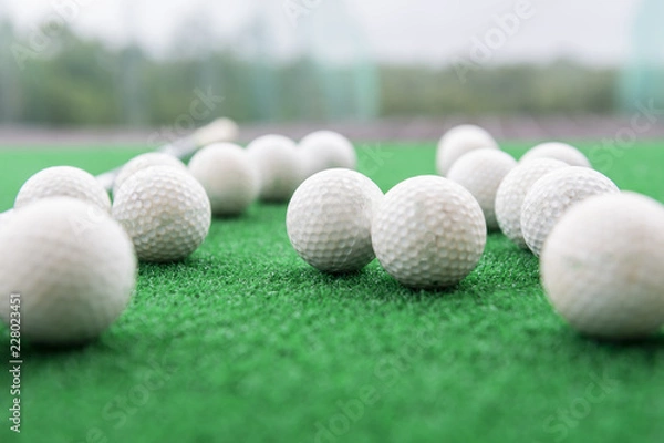 Obraz Golf club and balls on a synthetic grass mat at a practice range.