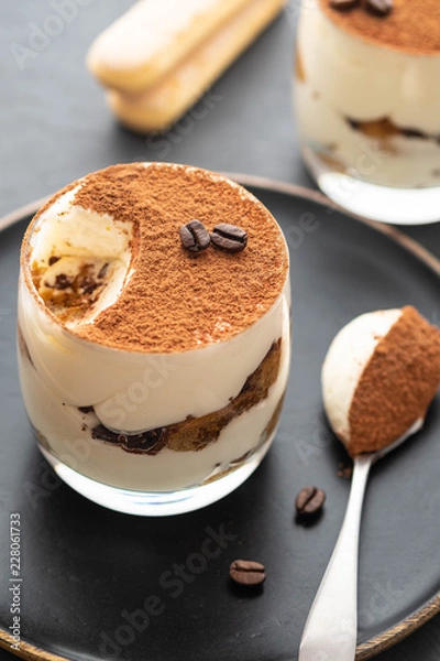 Fototapeta Delicious Italian dessert tiramisu, chocolate, cocoa and coffee beans on a black background. Copy space.