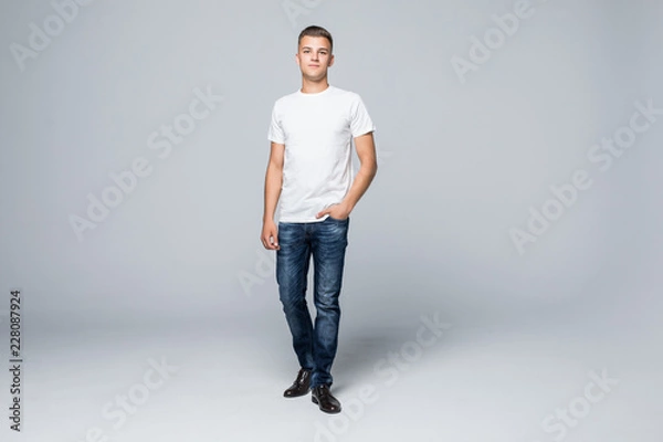 Obraz Full height of young happy casual man walking forward to the camera on white backround