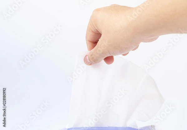 Fototapeta Woman hand pulling out white tissue paper from tissue box  for cleaning something on white background.
